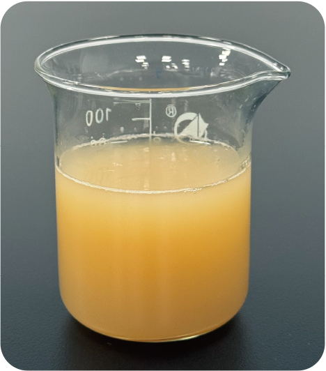 Beaker with pale orange liquid about two-thirds full, glass with measurement marks visible on a dark surface